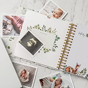 Shows baby album for girls open to large keepsake folder with photos surrounding it. 